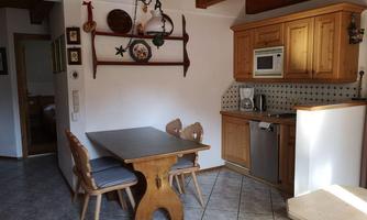 A cozy kitchen with wooden cabinets and a dining table. The room design is rustic and inviting.