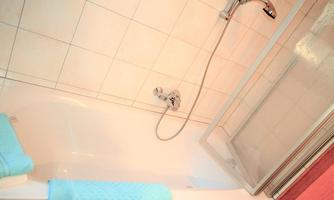 A bathroom with a bathtub and a shower. The towels are light blue and neatly folded.