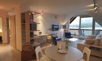 A modern living room with a dining area and a beautiful view. Large windows let in plenty of light and offer a view of the surroundings.
