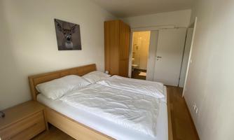 A simple bedroom with a double bed and wooden wardrobes. A picture of a deer hangs on the wall.