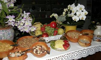 A beautiful table set with various types of fruit and breakfast ingredients. Among them are bowls with cereals, dried fruits, and fresh fruits.