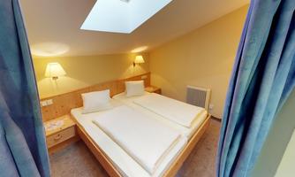 A cozy bedroom with two single beds and soft lighting. The skylight lets in plenty of daylight.