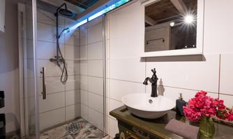 A modern bathroom with a shower and an elegant sink. Colorful tiles and fresh flowers create an appealing atmosphere.