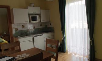 A modern kitchen with a dining table and wooden chairs. The window lets in plenty of light and the walls are painted in soft colors.