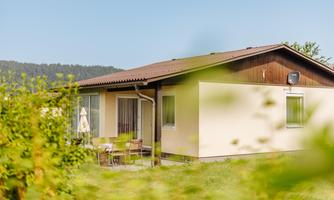A modern holiday home surrounded by greenery. It has a terrace with seating and a view of the countryside.
