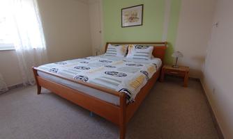 A cozy bedroom with a large bed and a nightstand. The room has bright light and simple decoration.