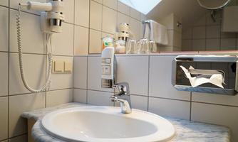 A modern bathroom with a marble sink and a towel holder. In the background, glasses and a paper towel dispenser can be seen.