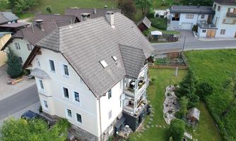 A large house with multiple floors and a well-maintained garden. The surroundings are green and offer a peaceful atmosphere.