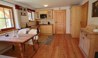 A cozy kitchen with wooden shelves and a dining area. The room has a warm, inviting character and plenty of natural light.