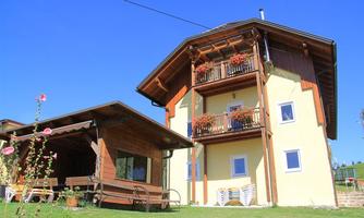 A charming two-story house with wooden elements and a balcony. The garden is well-maintained and invites relaxation.