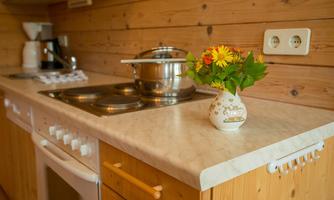 A modern kitchen with wooden paneling and a decorative bouquet of flowers in a vase. There is a cooking pot on the countertop and a coffee machine is visible.