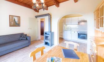 A cozy living room with a gray sofa and a dining area. The open kitchen is modern and well-equipped.