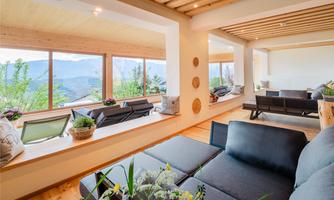 A modern living room with large windows that offer a stunning view of the mountains. The cozy furnishings invite you to relax.