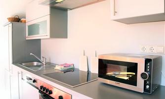 A modern kitchen with a stove, a microwave, and a sink. The kitchen elements are designed in a simple, light style.