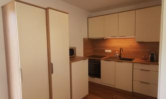 A modern kitchen with bright cabinets and a wooden countertop. The floor is made of wood and there is a small round table.