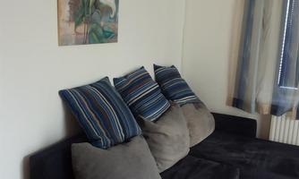 A cozy sofa with striped and gray cushions. A piece of artwork with plant motifs hangs on the wall.
