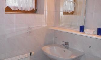 A modern bathroom with two sinks and a large mirror. Bright tiles and a window provide natural light.