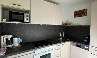 A modern kitchen with bright cabinets and a black countertop. It is equipped with various appliances such as a stove and a microwave.