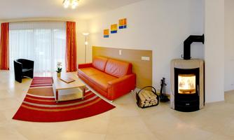 A modern living room with a red sofa and a coffee table. A cozy fireplace creates a warm atmosphere.