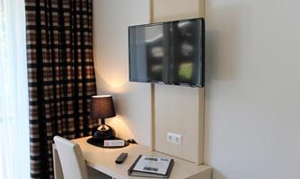 A modern room with a television on the wall. On the table stands a lamp and an information brochure.