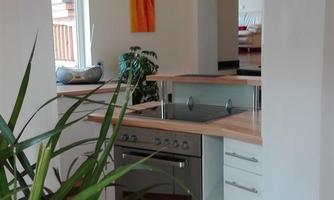 A modern kitchen with a wooden countertop and stainless steel appliances. Green plants add a fresh touch to the room.