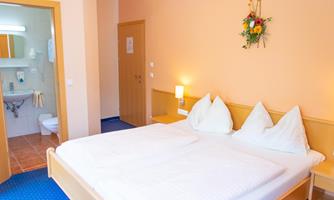A cozy bedroom with a double bed and bright walls. The room has a bathroom and pleasant lighting.