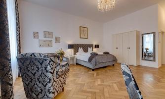 A stylish bedroom with a large bed and elegant furniture. The walls are light and tastefully decorated.
