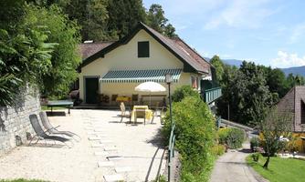 A cozy house with a terrace, surrounded by trees and green spaces. The terrace is furnished with chairs and a table for relaxing hours.