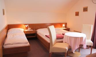 A cozy room with two beds and a small table. The walls are painted in soft colors and there is gentle lighting.
