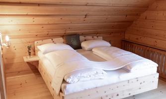 A cozy bedroom with a wooden double bed. The walls are made of wood paneling and the room exudes a warm atmosphere.