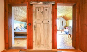 A rustic entrance with a white wooden door and a warm wooden interior. The rooms on both sides are bright and cheerfully furnished.