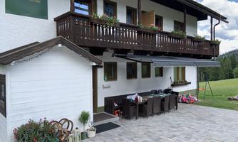 A cozy house with a balcony and a terrace. The outdoor area is equipped with a table and chairs, surrounded by a beautiful landscape.