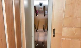 A narrow cabinet with a stainless steel frame and several hooks. The door opens to reveal the contents.