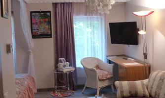 Junior suite with a bed, a seating area and a television. Large windows provide plenty of natural light.