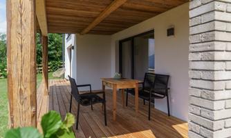 A cozy terrace with a wooden floor and a table. Two chairs are placed to enjoy the surroundings.