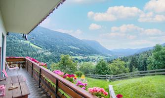 A beautiful view from the balcony with colorful flowers. In the background, there are green hills and a clear sky.