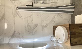 A modern bathroom with a stylish shower and a round mirror light. The wash area is made of wood and has an elegant design.
