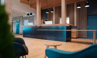 A modern reception area with an elegant wooden reception desk and a minimalist design. The warm color tones and lighting create an inviting atmosphere.