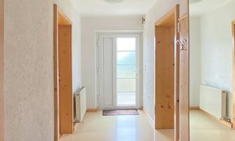 A bright hallway with two doors on the left and right sides. The window at the end provides natural light and a welcoming atmosphere.