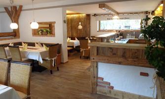 A cozy restaurant with wooden furniture and white tablecloths. The atmosphere is warm and inviting.