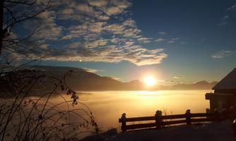A beautiful sunrise over misty mountains. The landscape is covered in snow and the sky displays a play of colors of blue and gold.