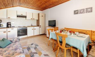 A cozy kitchen with a dining table and wooden furniture. The atmosphere is bright and inviting.