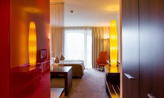 A modern hotel room with warm light and large windows. The room has a stylish decor and an inviting view outside.