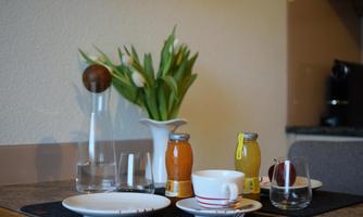 A beautifully set table with plates, glasses, and various drinks. In the background, there is a vase with fresh tulips.