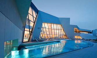 A modern building with large windows and a sparkling pool. The atmosphere is calm and inviting, perfect for relaxation.