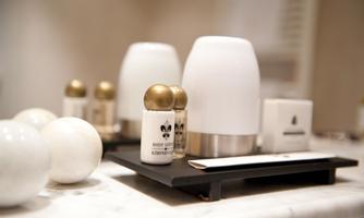 Elegant bathroom accessories on a marble table. The set includes a fragrance dispenser, lotion, and other care products in stylish packaging.