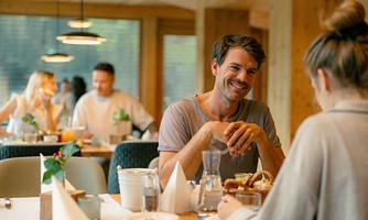 A cozy restaurant with wooden elements. A man and a woman are enjoying breakfast and seem to be having a good conversation.