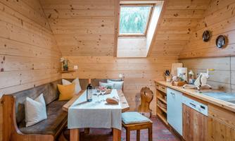 A cozy kitchen with wooden paneling and a large window. The table is set and invites you to eat.