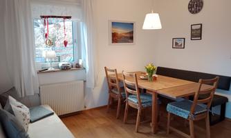 A cozy dining area with a wooden table and chairs. The room is bright and inviting with decorative elements on the walls.