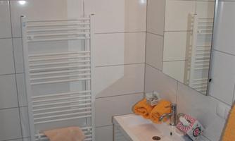 A modern bathroom with bright tiles and a sink. Towels in warm colors and a towel warmer create a cozy atmosphere.